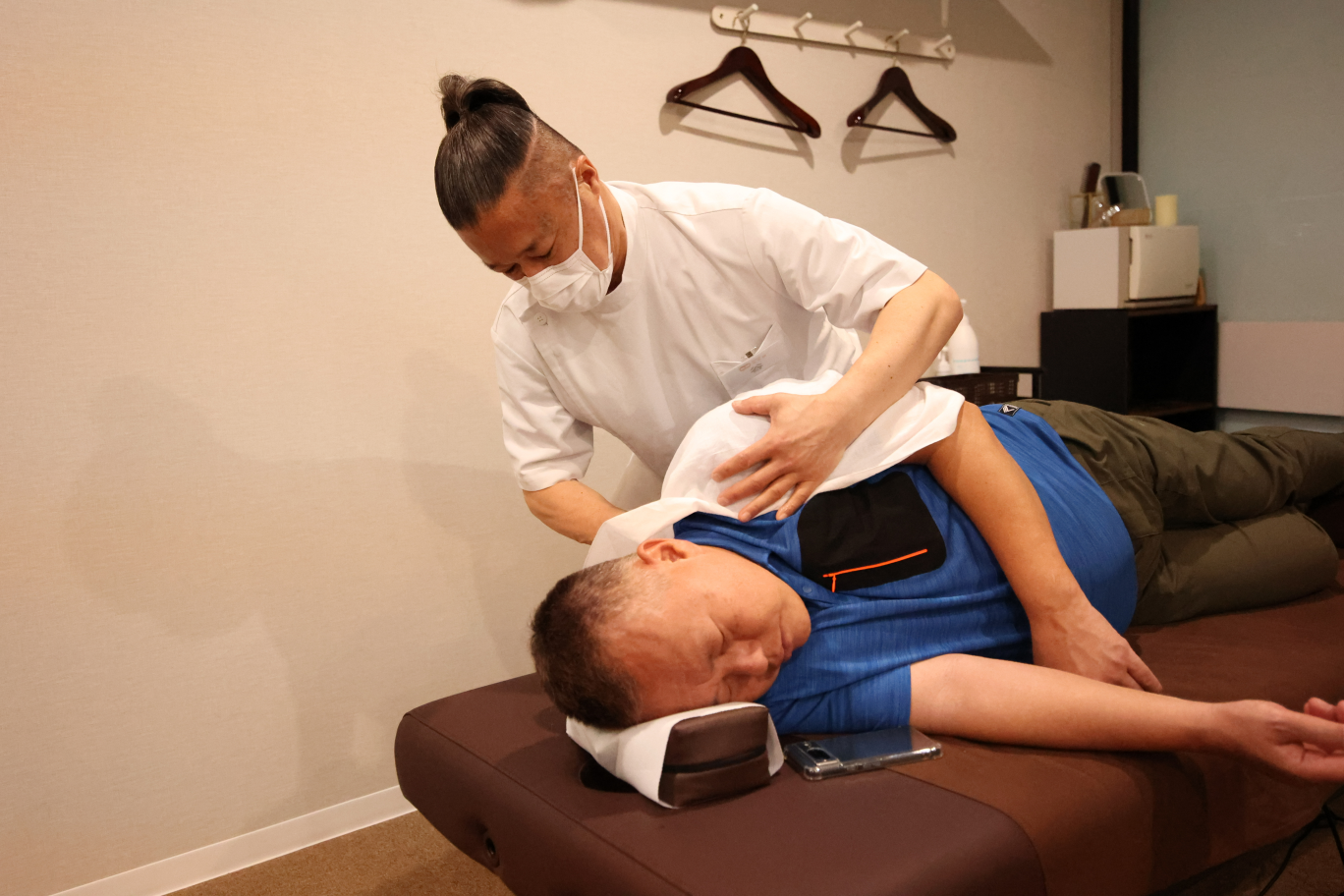 マスクをして肩のマッサージをする人