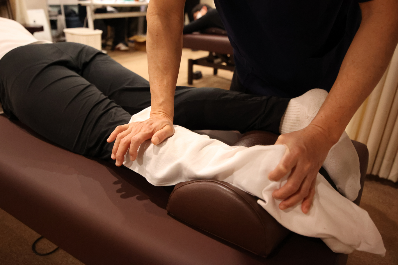 布を被せ腿を揉む人