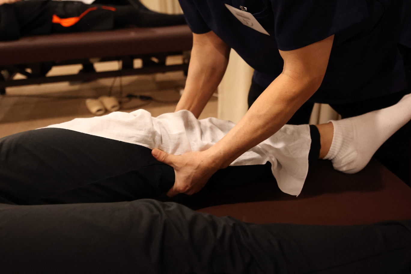 布を被せ足を揉む人