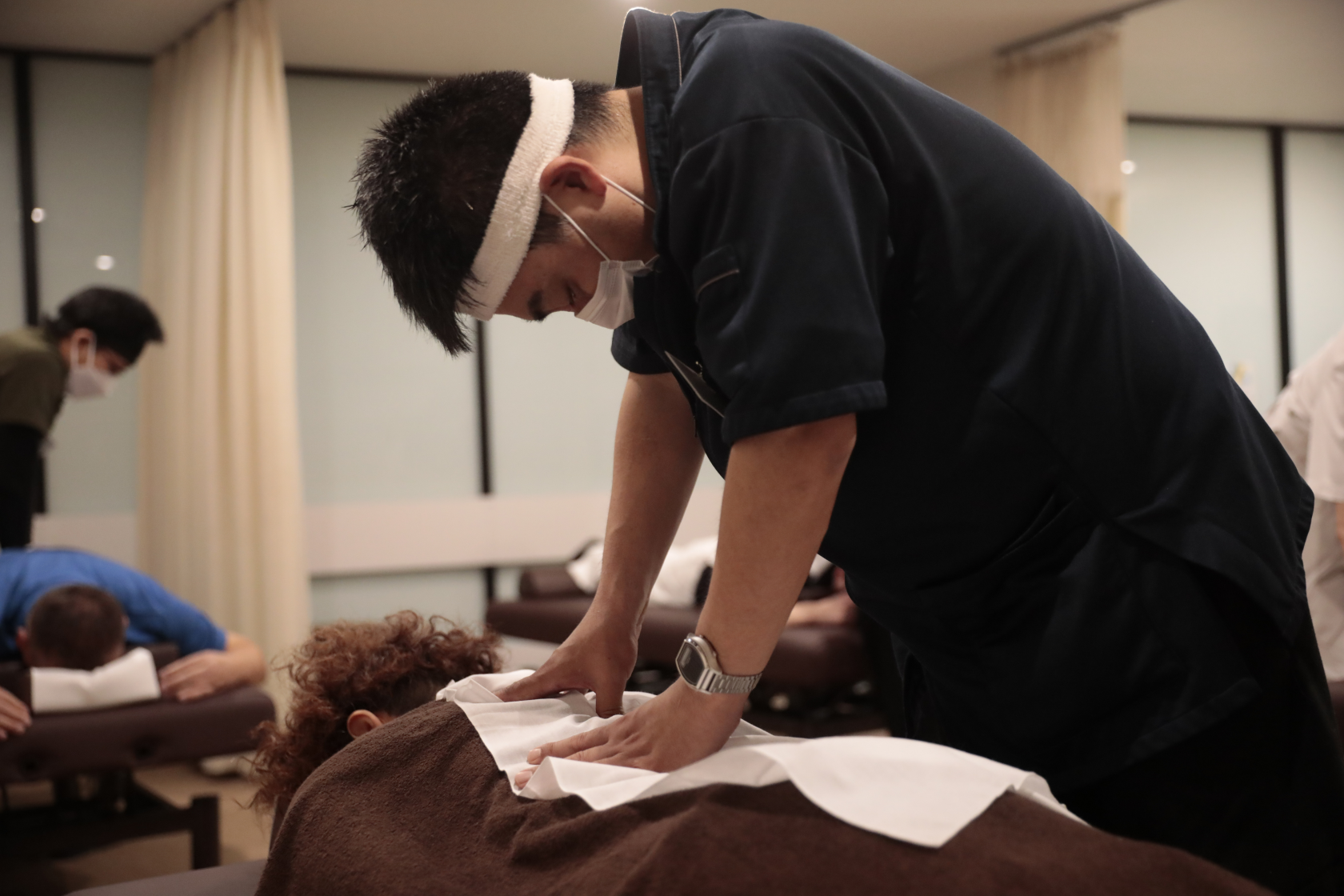 鉢巻を締めマッサージをする人