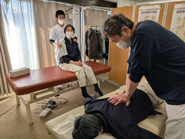 訪問チームが背中のマッサージをしている